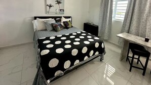 A bedroom with a bed, a desk, and a chair.