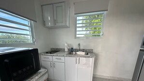 A small kitchen with white cabinets, a granite countertop, a sink, and a microwave.