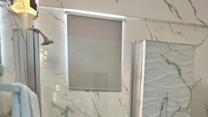 Un baño moderno con ducha de vidrio, azulejos de mármol y un inodoro.