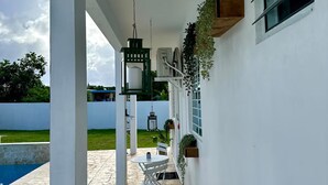 Un patio cubierto al aire libre con piscina, paredes blancas y un farol colgante.