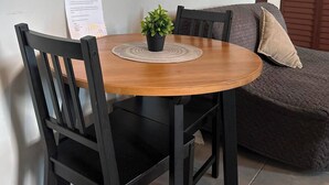 Uma mesa de madeira redonda com uma cadeira preta, uma pequena planta em vaso e um menu na parede.