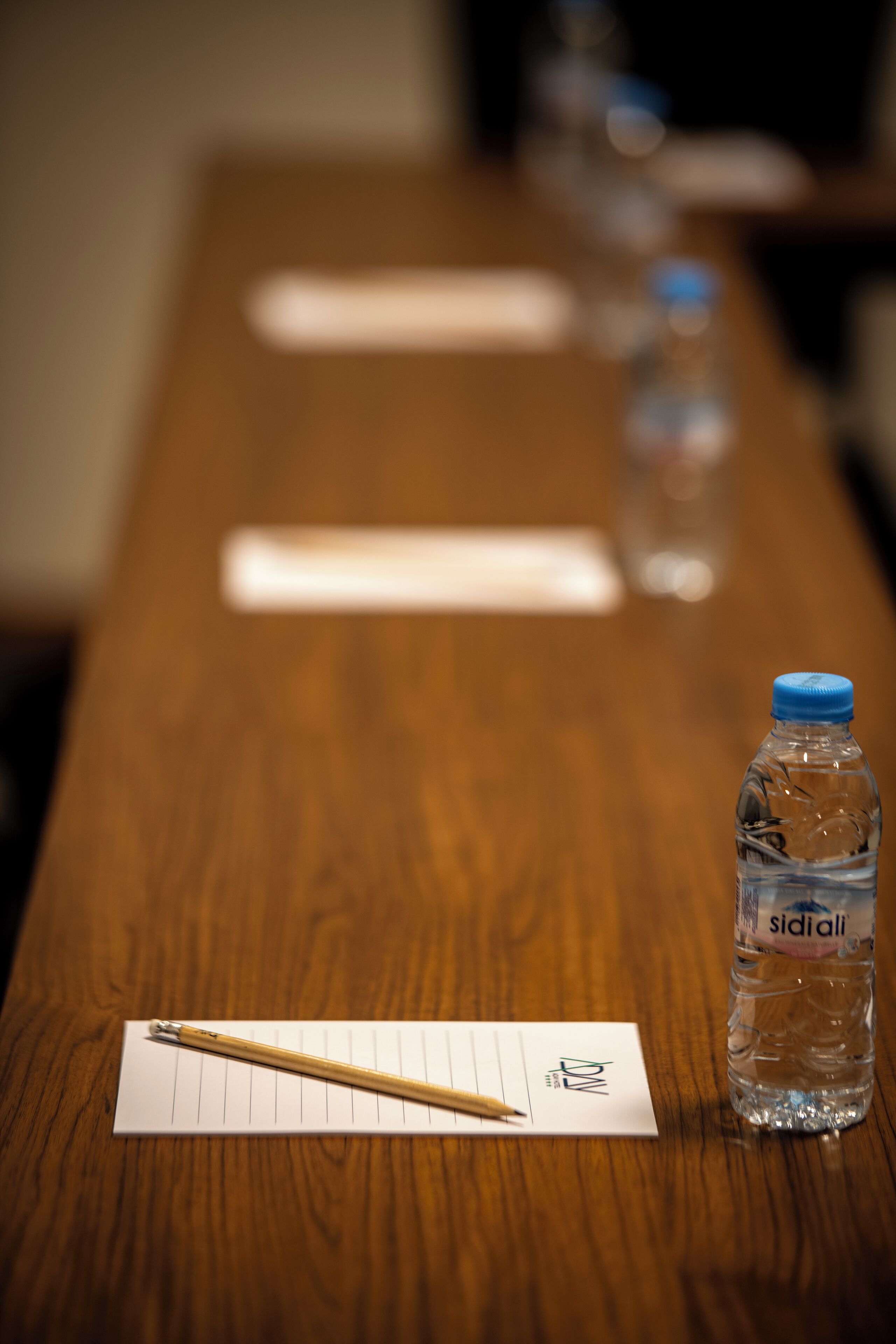 A wooden table with a water bottle, a pencil, and a check sheet.
