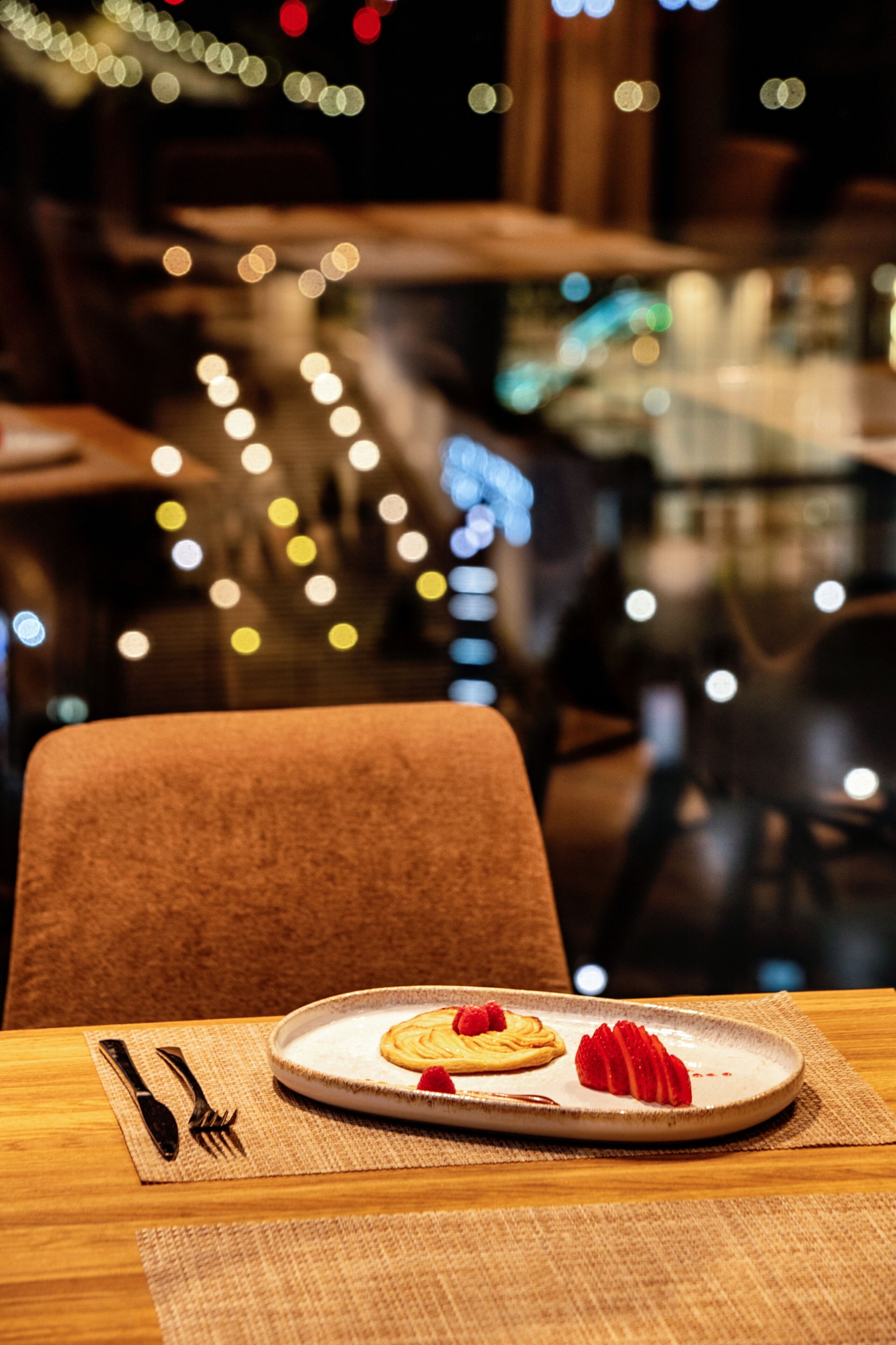 A dining table with a plate of food, cutlery, and a placemat.