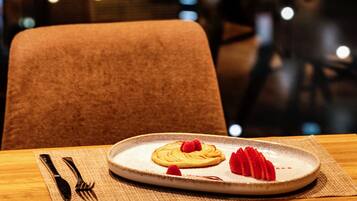 A dining table with a plate of food, cutlery, and a placemat.