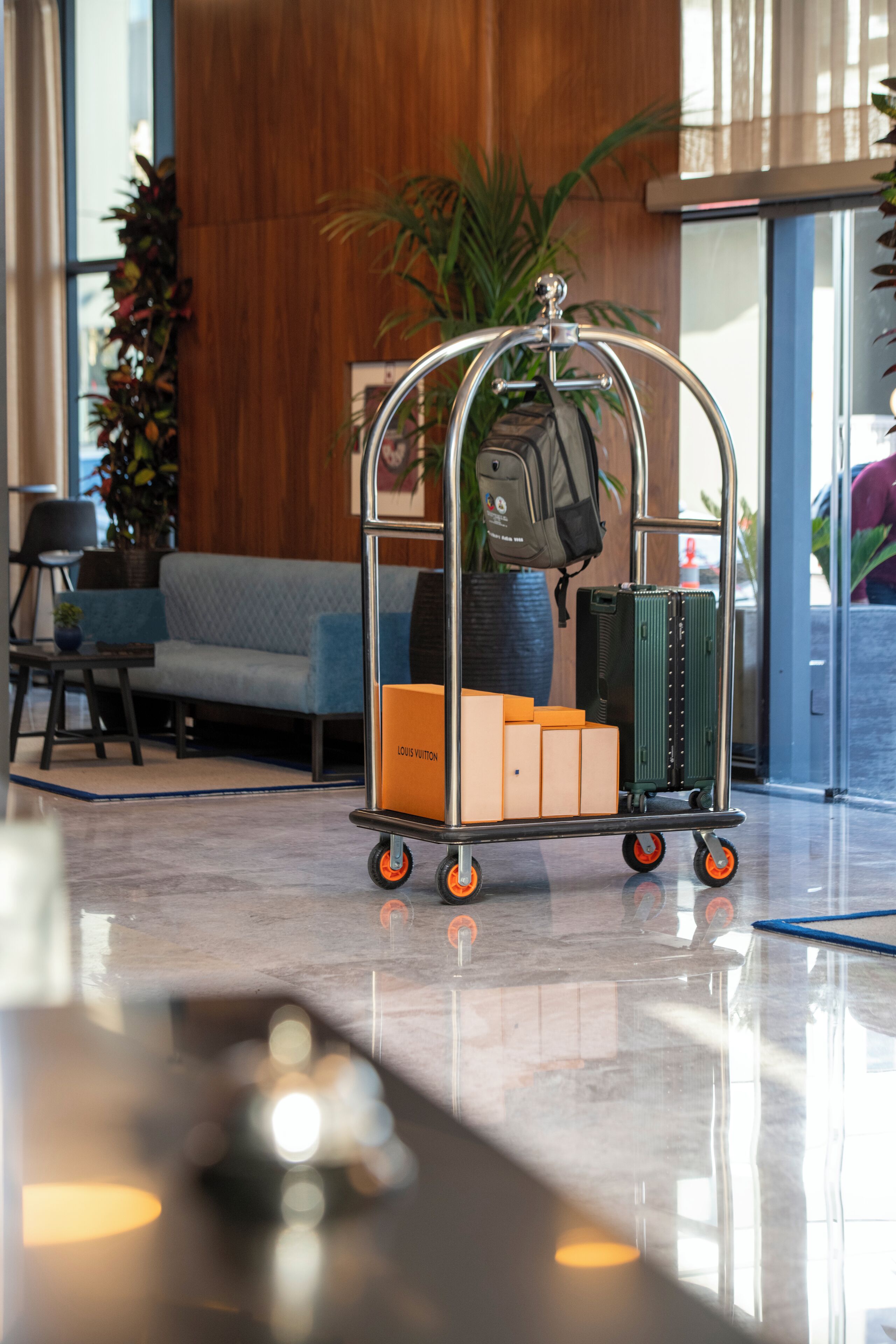 Un chariot à bagages avec une valise et des cartons dans le hall d’un hôtel.
