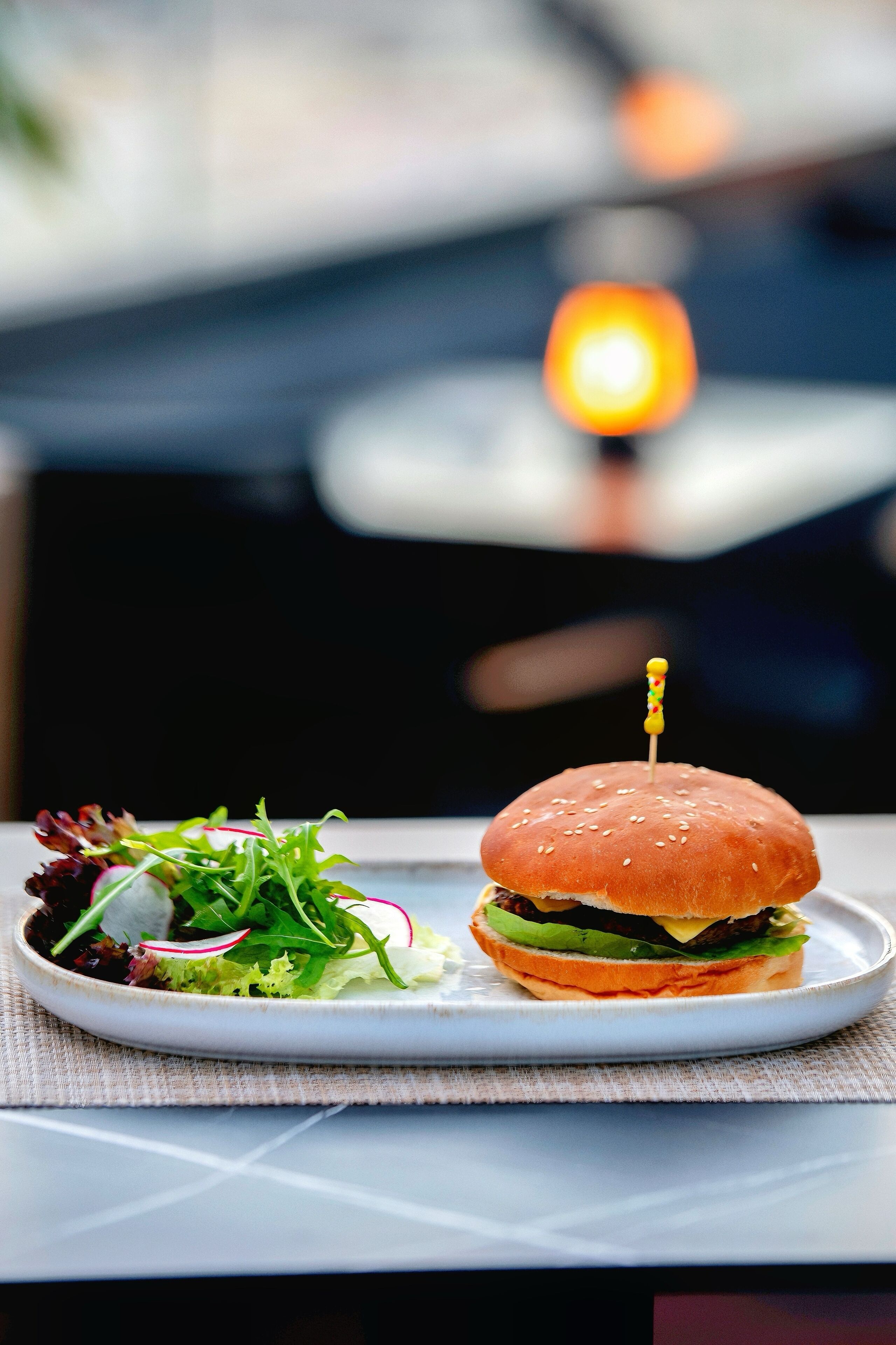 A plate with a burger and a side salad on a table.