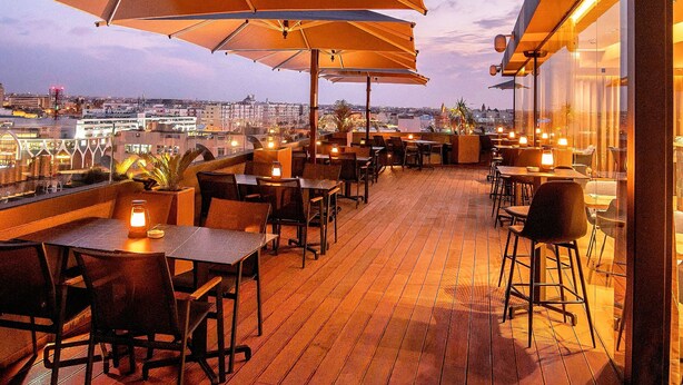 An outdoor terrace with wooden flooring, tables, chairs, and large umbrellas providing shade. - ADAY Hotel Casablanca (Casablanca)