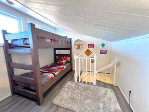 A bunk bed with a striped blanket, a white staircase, and a wall with various signs including one that says 'Ski Area Boundary.' - Baldy Mountain Basecamp - Pet Friendly! - Free Shuttle Access (Breckenridge)