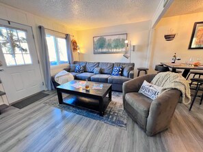 A living room with a sofa, coffee table, and a dining area with a table and chairs. - Baldy Mountain Basecamp - Pet Friendly! - Free Shuttle Access (Breckenridge)