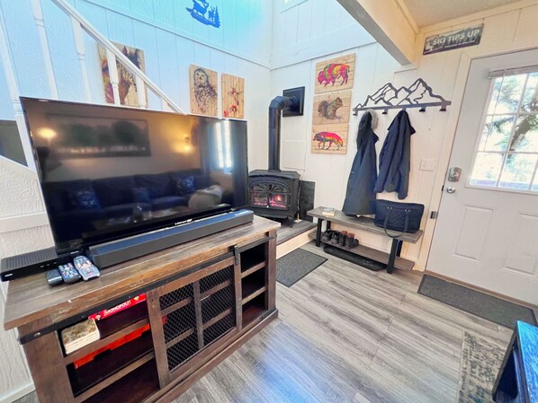 A living room with a large flat-screen TV, a fireplace, and a coat rack. - Baldy Mountain Basecamp - Pet Friendly! - Free Shuttle Access (Breckenridge)