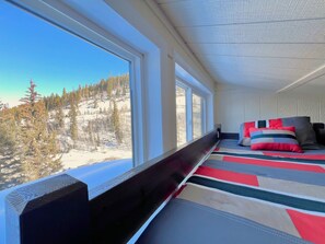 Ein Zimmer mit einem Bett, großen Fenstern und Blick auf eine verschneite Landschaft.