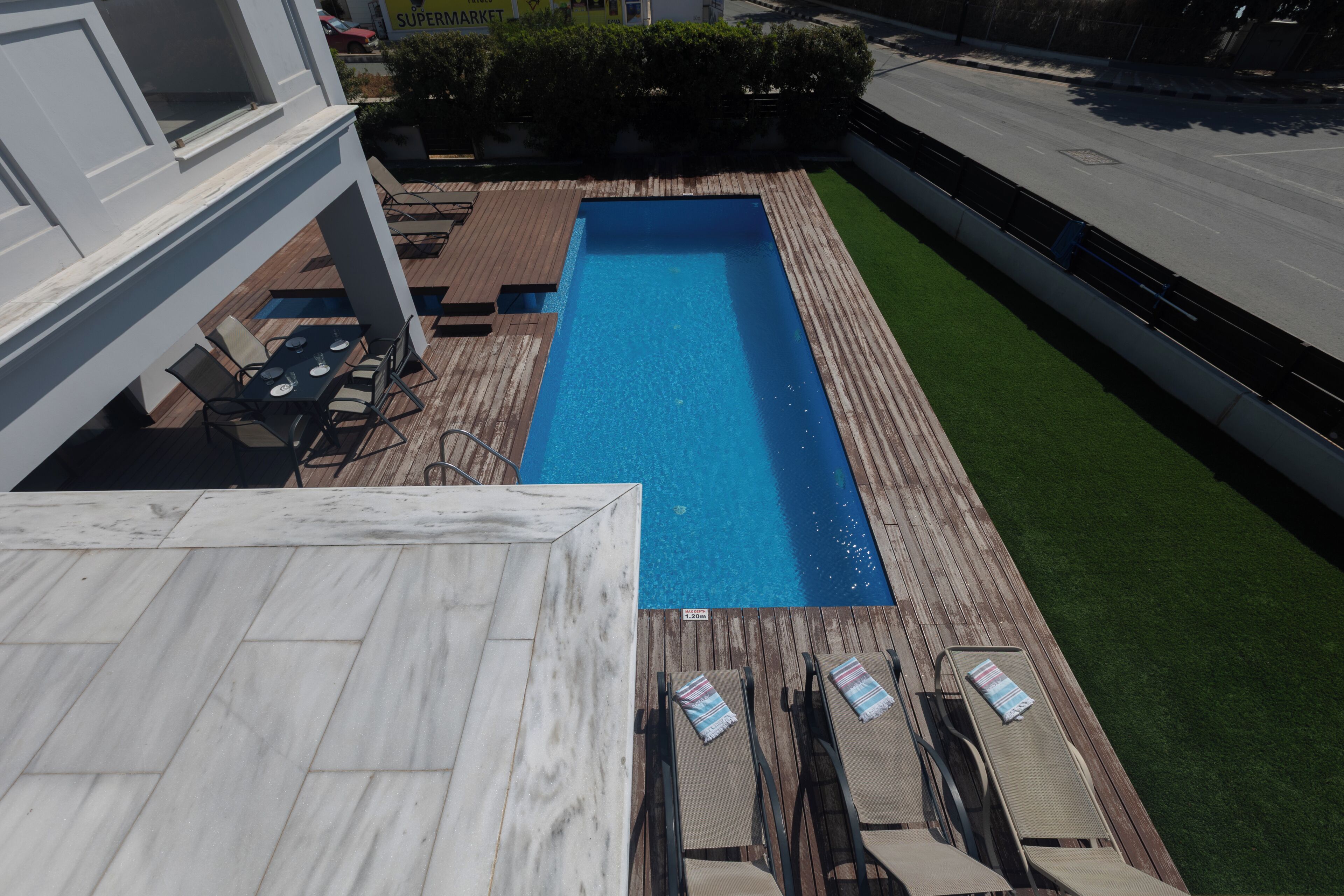 Une piscine rectangulaire avec une terrasse en bois et des chaises longues.