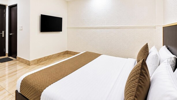 Une chambre d’hôtel avec un lit, un téléviseur fixé au mur et une porte.