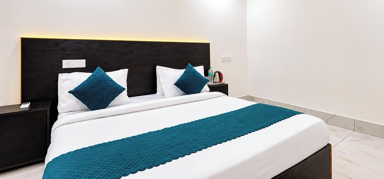 Habitació d'hotel amb un llit, una tauleta de nit i una cadira de nit.