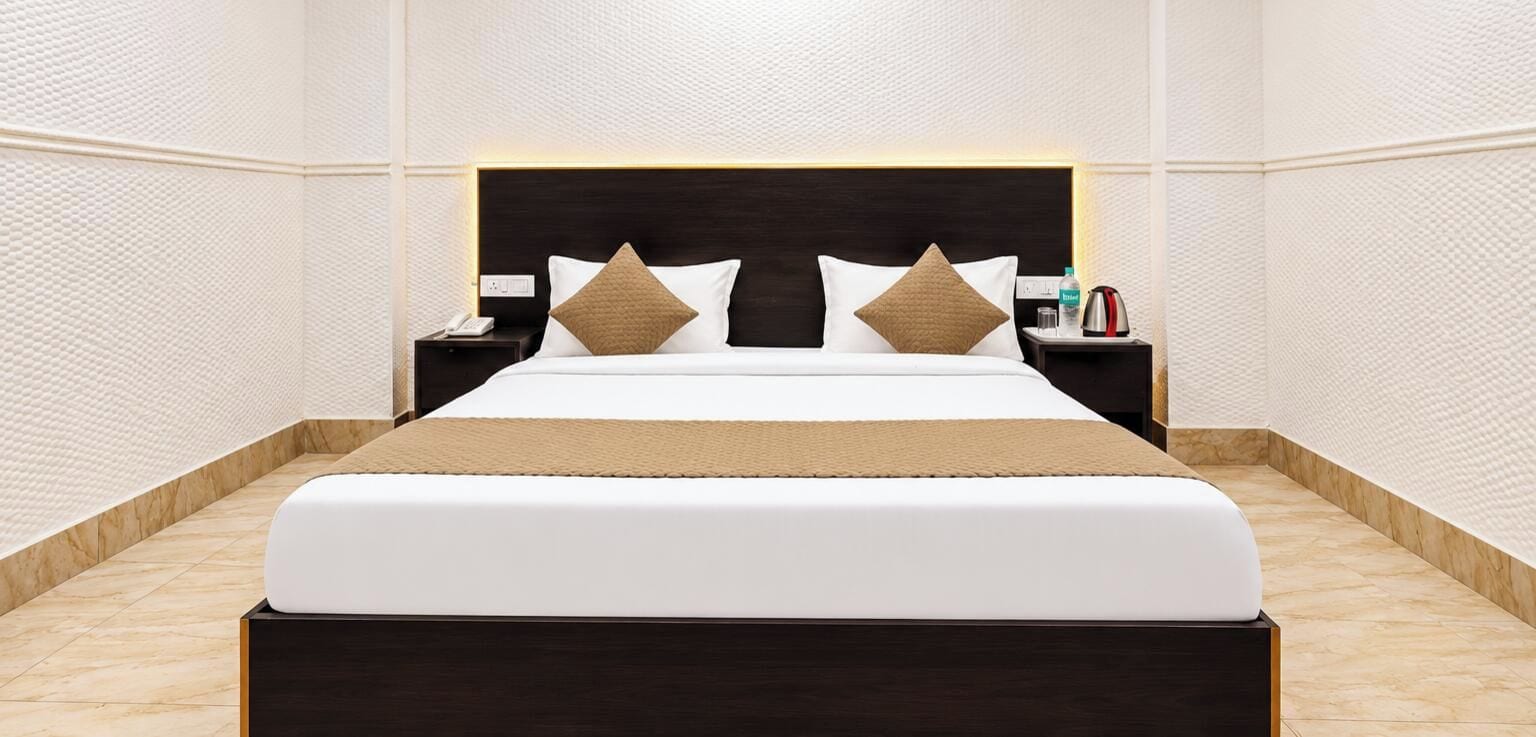 Una habitación de hotel moderna con una cama grande, dos mesitas de noche y un cabecero con iluminación integrada.