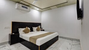 A bedroom with a bed, nightstands, a TV, and an air conditioning unit. - Mauryan Signature hotel Devli Khanpur (New Delhi)