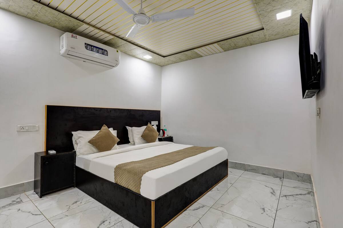 A bedroom with a bed, nightstands, a TV, and an air conditioning unit.