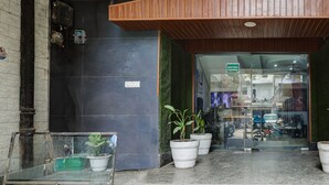 A building entrance with a wooden ceiling, a glass door marked "ENTRY", and potted plants on the steps. - Mauryan Signature hotel Devli Khanpur (New Delhi)