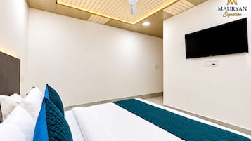 A hotel room with a bed, a flat-screen TV mounted on the wall, a ceiling fan, and a marble floor.