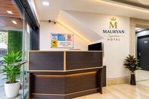 A reception desk with a sign indicating check-in at 12:00 PM and check-out at 11:00 AM.
