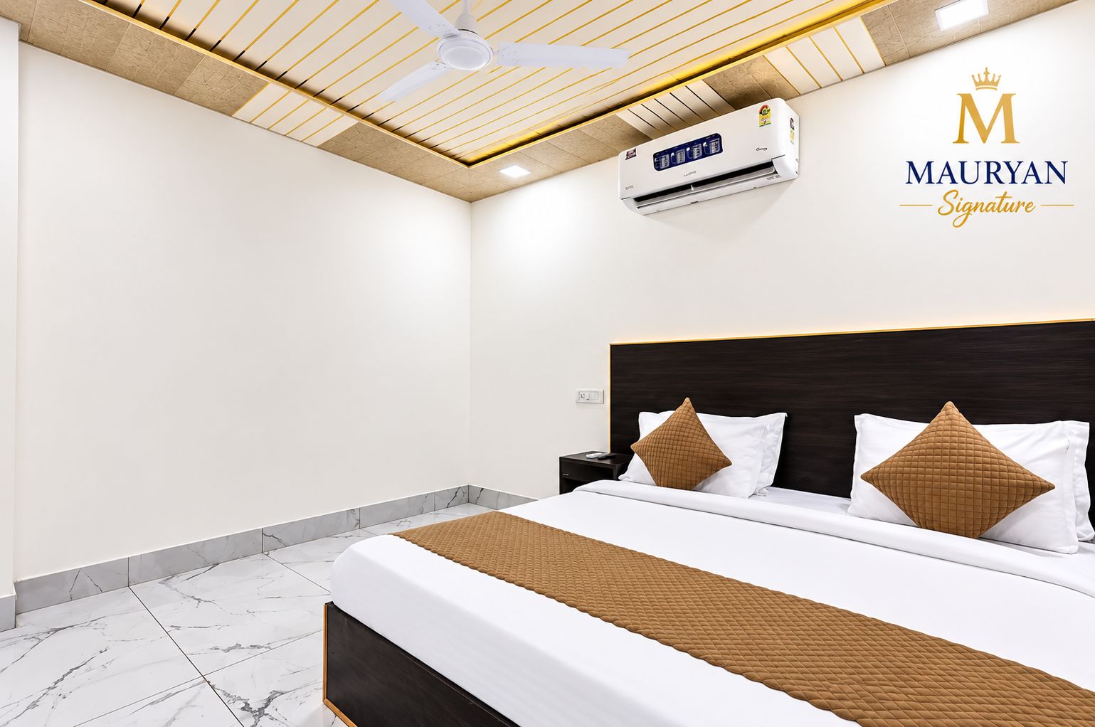 A hotel room with a bed, a nightstand, an air conditioning unit, and a ceiling fan.