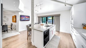 Una cocina moderna con una isla grande, armarios blancos y vistas al exterior.