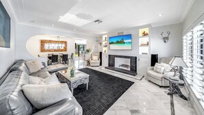 Una sala de estar moderna con sofá, mesa de centro, chimenea, televisor y objetos decorativos.