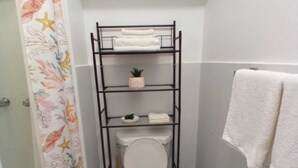 Un baño pequeño con inodoro, un estante con toallas y cortina de ducha.