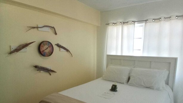Un dormitorio con una cama, un reloj de pared y obras de arte colgadas.