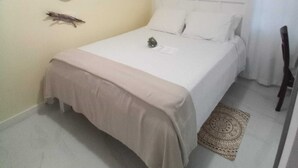 Un dormitorio con una cama, un reloj de pared y un ventanal con cortinas.