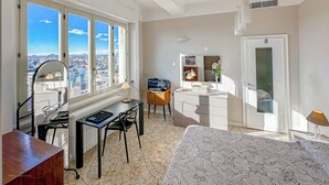 Un dormitorio con una ventana grande, un escritorio, una silla, una cama y un aparador.