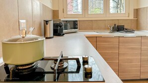 A modern kitchen with a gas stove, a kettle, a microwave, and a sink.
