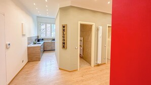 A modern apartment with a kitchen, a living area, and a bathroom. There is a 'WELCOME' sign on the wall.