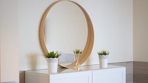 A white cabinet with three potted plants and a large mirror.