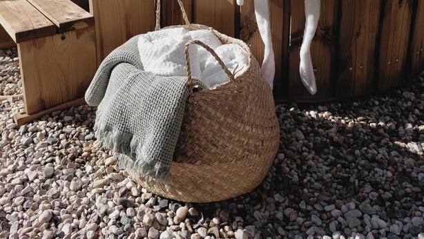 Un espace extérieur aménagé avec des sièges en bois, comprenant un banc et un panier tressé.