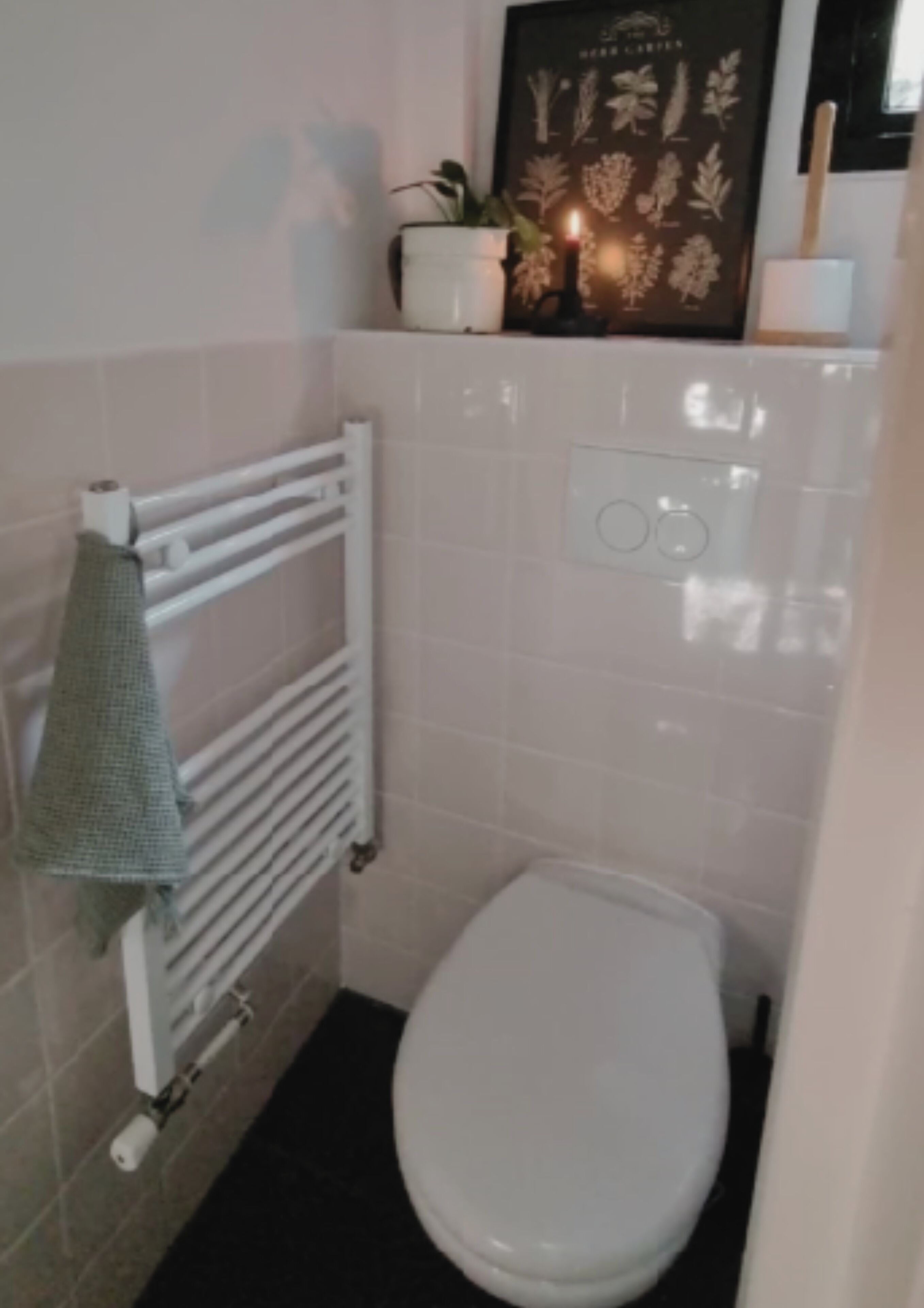 A small bathroom with a white radiator, a white toilet, and a towel hanging on the radiator.