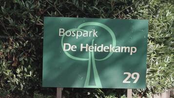 Un panneau vert portant l’inscription « Bospark De Heidekamp 29 » sur un fond de feuillage dense.
