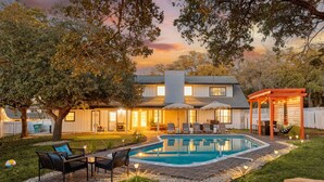 Un jardin avec une piscine, un espace salon extérieur et une terrasse couverte.
