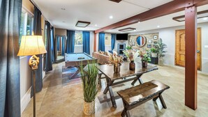 A spacious living area with a pool table, a dining table with chairs, and a sofa.