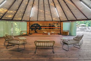 A covered outdoor seating area with wicker furniture and a central table.