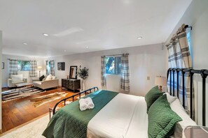 A hotel room with a bed, a sofa, a desk, and a window with curtains.