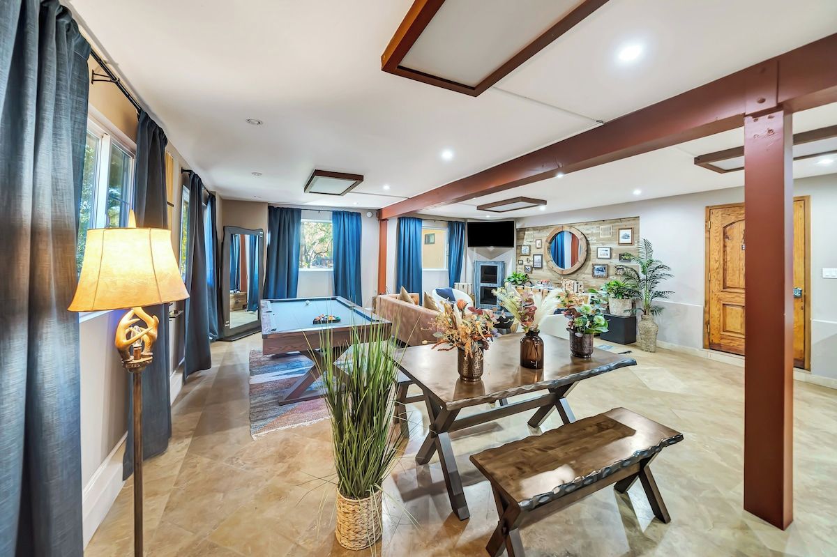 A spacious living area with a billiards table, a dining table with chairs, and a sofa.