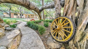 A stone pathway leading to a rustic building with a large yellow wheel.