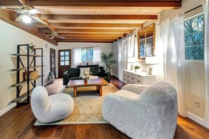 A spacious living room with a wooden ceiling, a green sofa, a white armchair, and a coffee table.