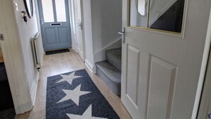 A hallway with a star-patterned rug, a blue door, and a staircase leading to an upper floor.