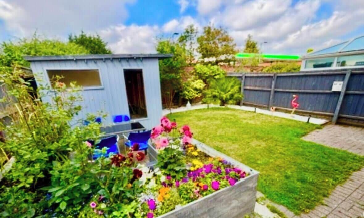 A garden with a raised flower bed, a small shed, and a fenced yard.