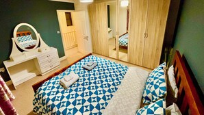 A bedroom with a bed, a dresser, a mirror, and a wardrobe.
