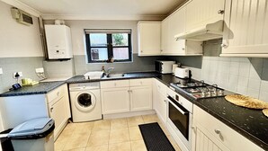 A compact kitchen with a washing machine, a sink, a stove, and a window.