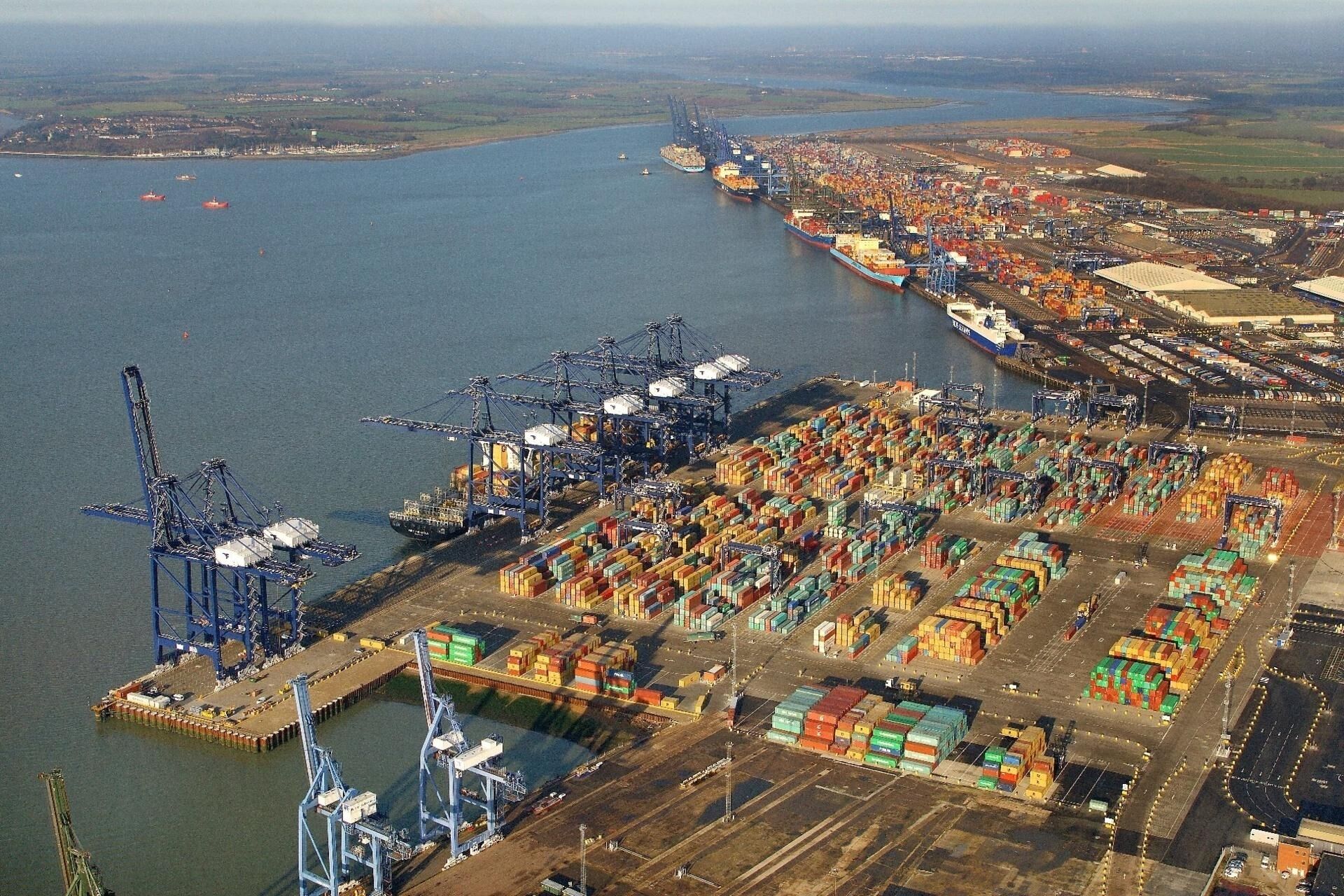 An aerial view of a port with multiple shipping containers and cranes.