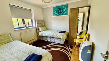 Une chambre avec deux lits, une fenêtre donnant sur un beau paysage, un grand miroir et un radiateur.